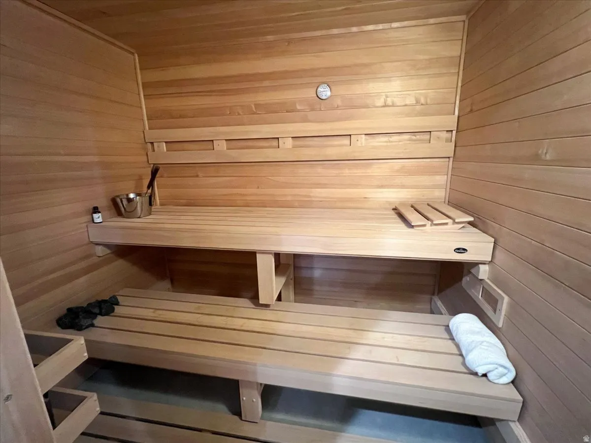 Wood-paneled sauna featuring multiple built-in benches and a wall-mounted thermometer