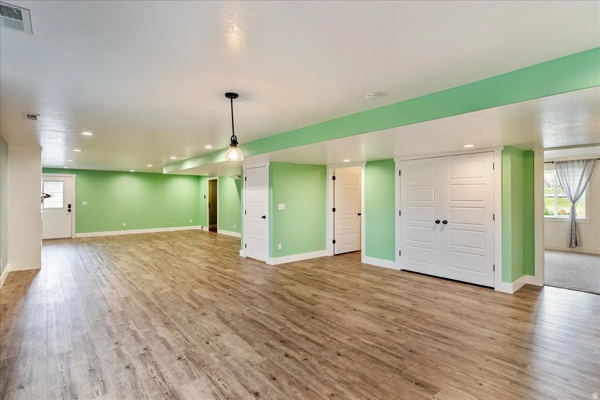 Spacious interior featuring wood-finish flooring, recessed lighting, a pendant light fixture, and white bi-fold doors