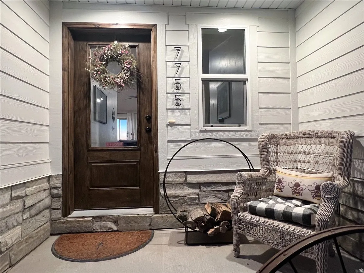 Wood entry door with glass panel, white siding, and stone veneer accents