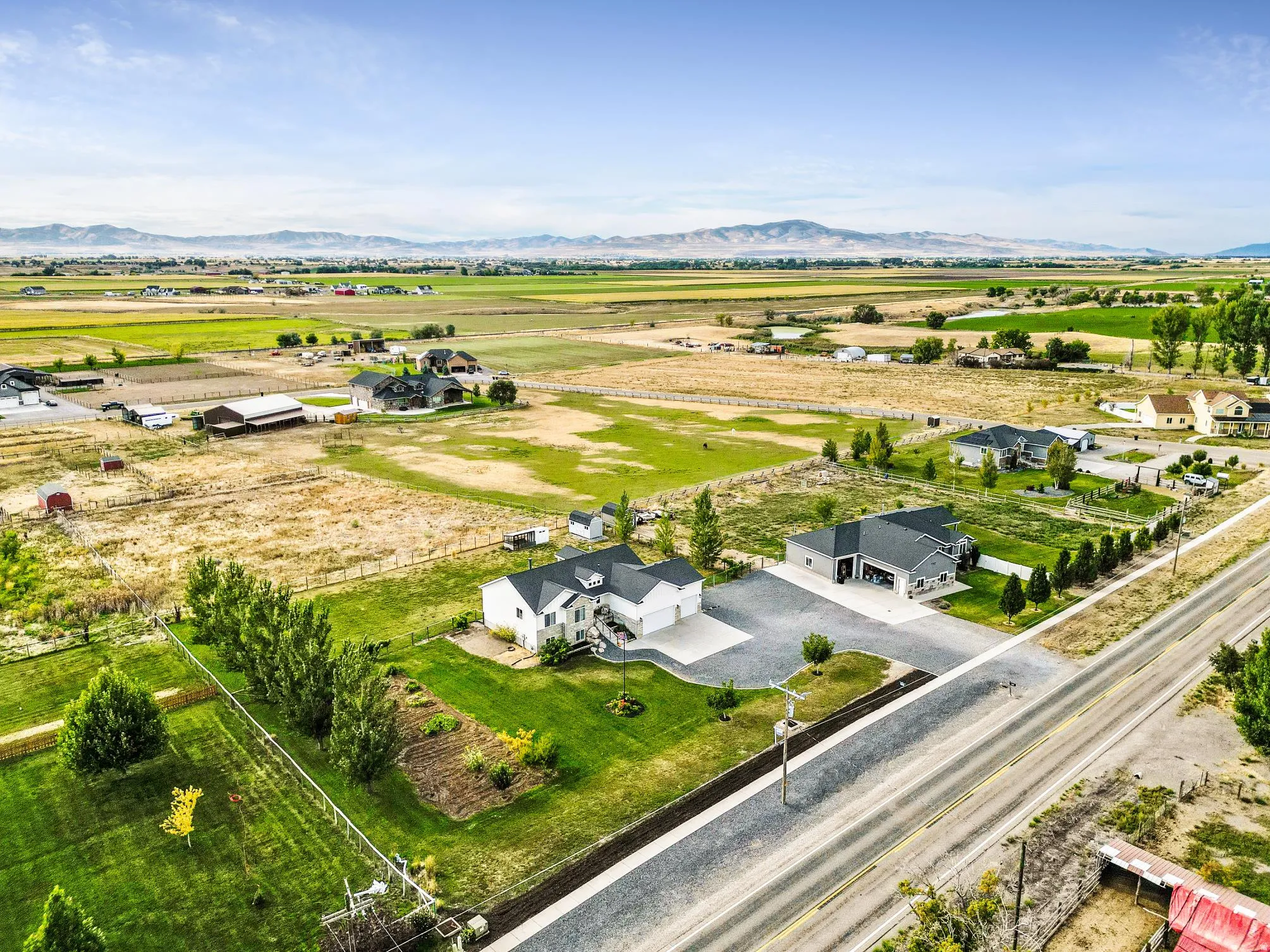Expansive property featuring two distinct residences, a detached garage, and a gravel driveway