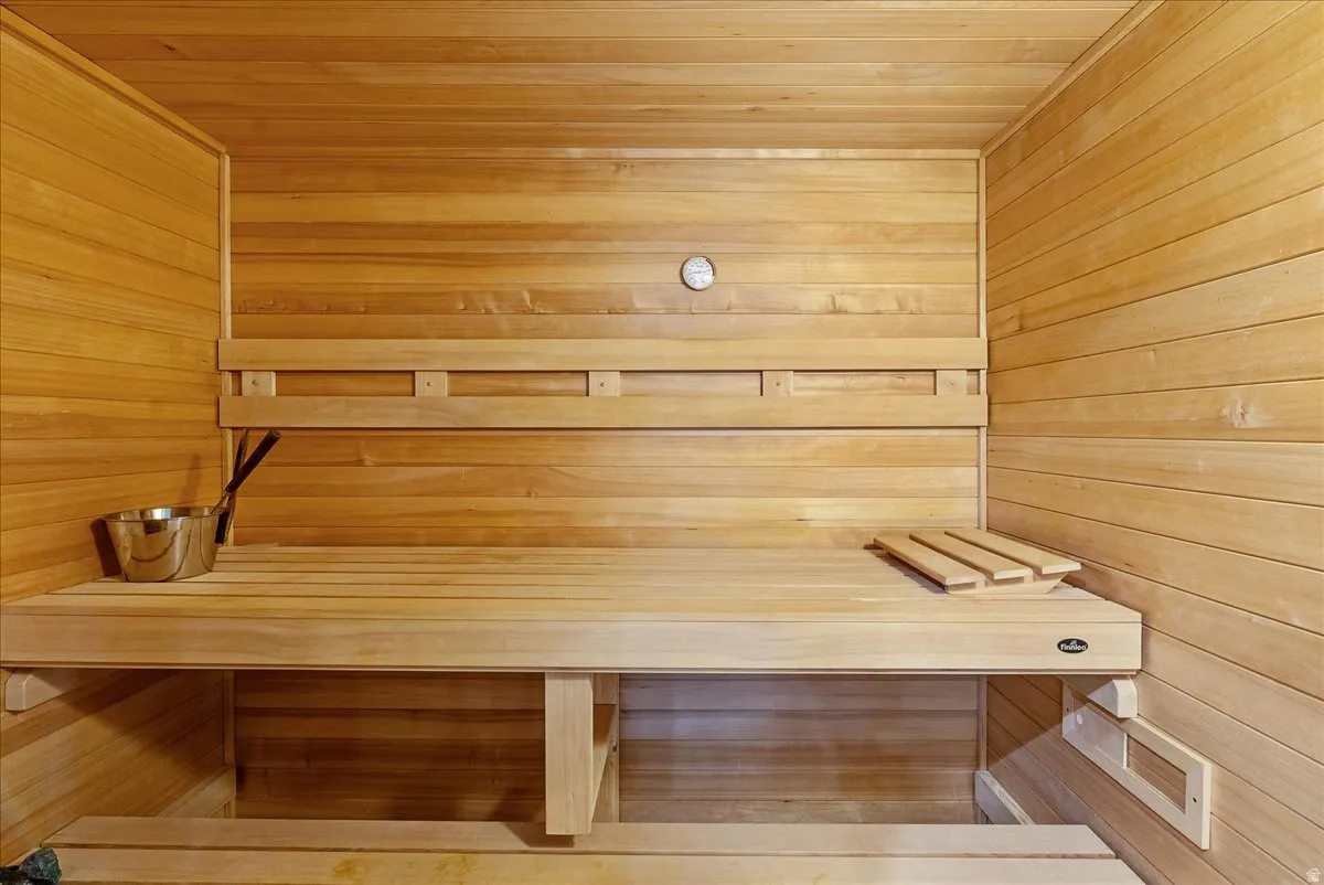Wood-paneled sauna featuring built-in wooden benches and a wall-mounted temperature gauge