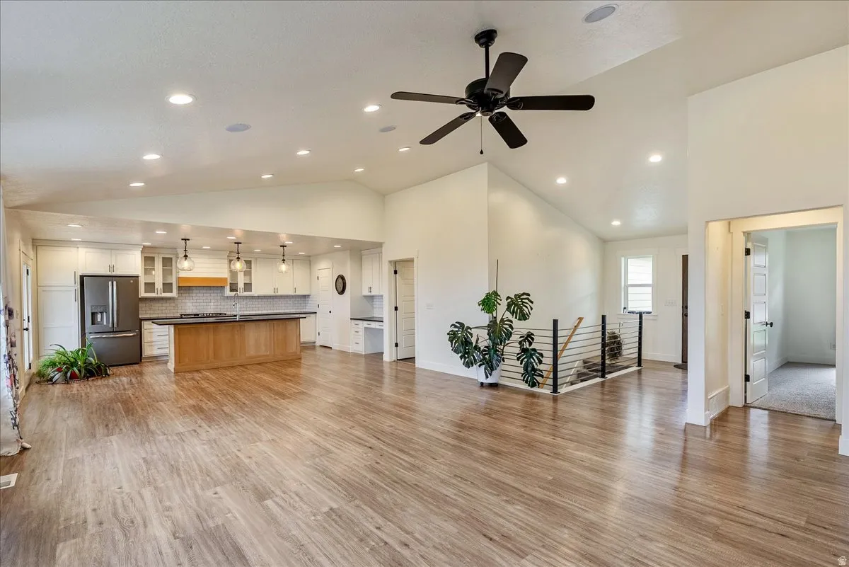 Open-concept room featuring wood-finish flooring, vaulted ceilings, recessed lighting, and a modern kitchen with a large island