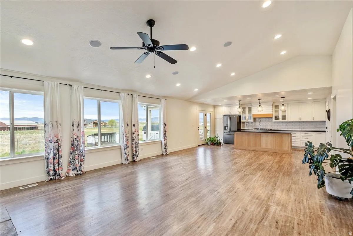 Vaulted ceilings, recessed lighting, and wood-finish flooring characterize this open-concept space