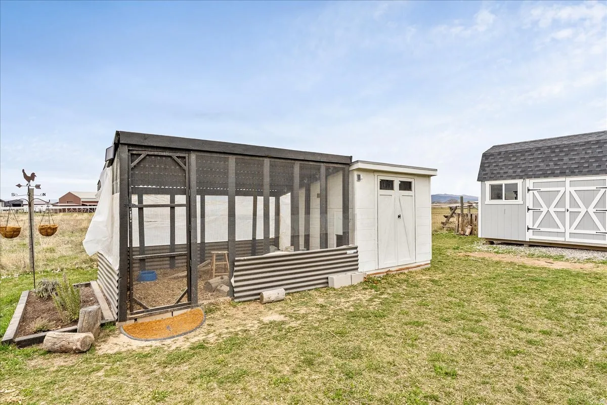 Enclosed structure with screen panels, corrugated metal siding, and an attached white storage shed
