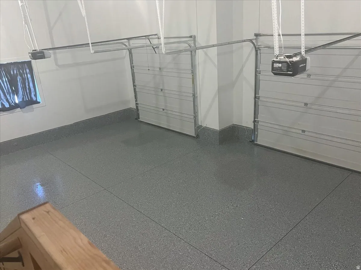 Two overhead garage doors, automatic door openers, and a gray speckled epoxy floor