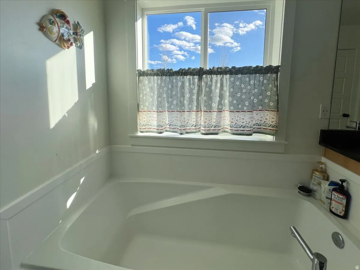 Soaking tub with a polished chrome faucet, a large window, and wainscoting