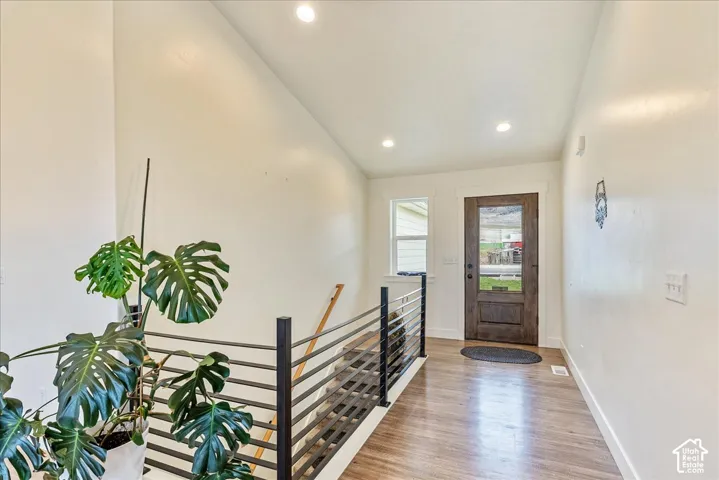Wood-finish flooring, recessed lighting, and a dark wood entry door with a clear glass insert