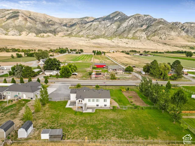 Two-story residence with a rear deck, expansive lawn, and multiple storage sheds