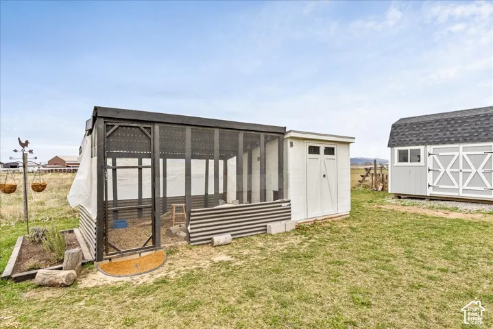 Enclosed structure with screen panels, corrugated metal siding, and an attached white storage shed