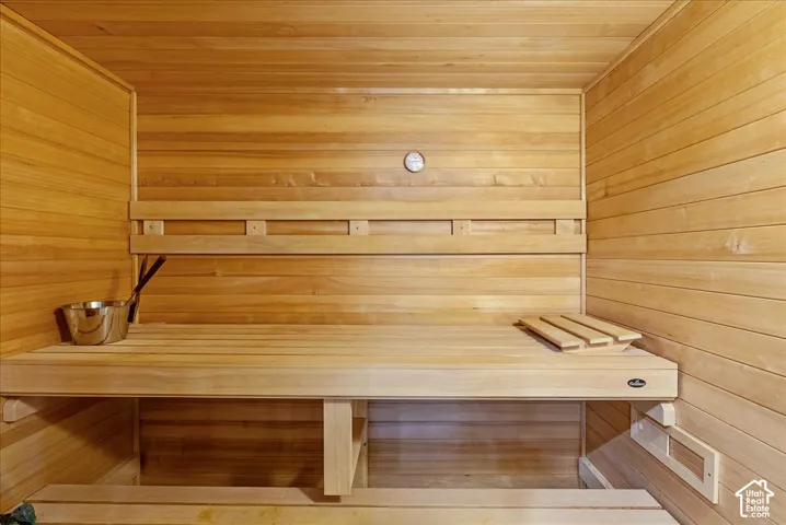Wood-paneled sauna featuring built-in wooden benches and a wall-mounted temperature gauge