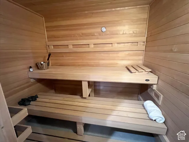 Wood-paneled sauna featuring multiple built-in benches and a wall-mounted thermometer