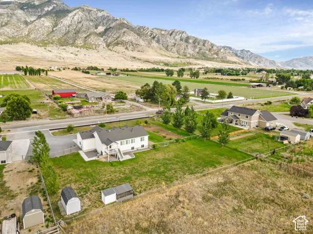 Expansive property featuring a large lawn area, mature trees, mountain backdrop, and multiple outbuildings