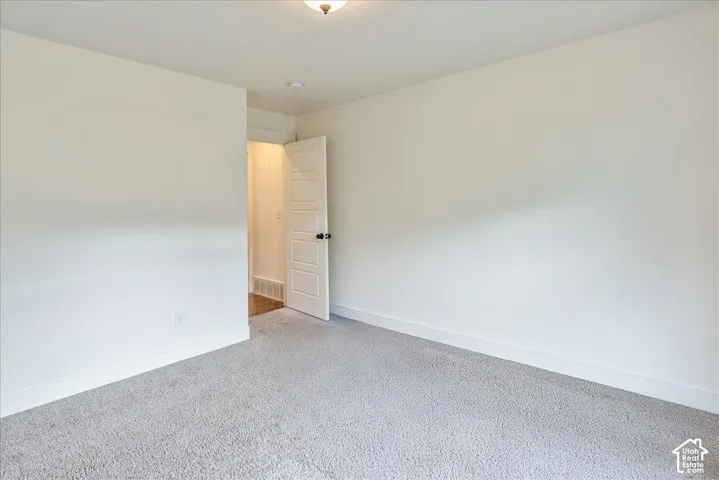 Neutral wall color, light gray carpet flooring, white trim, and a paneled interior door with dark hardware