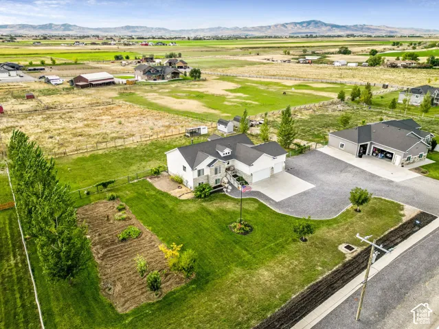 Expansive property featuring a main residence, detached garage, manicured lawn, and a cultivated garden bed
