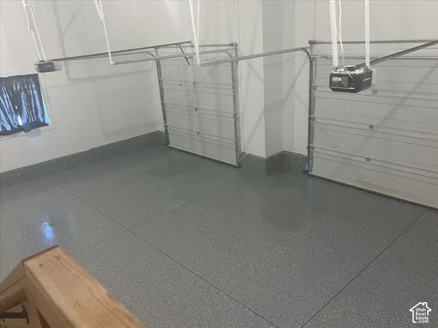 Two overhead garage doors, automatic door openers, and a gray speckled epoxy floor