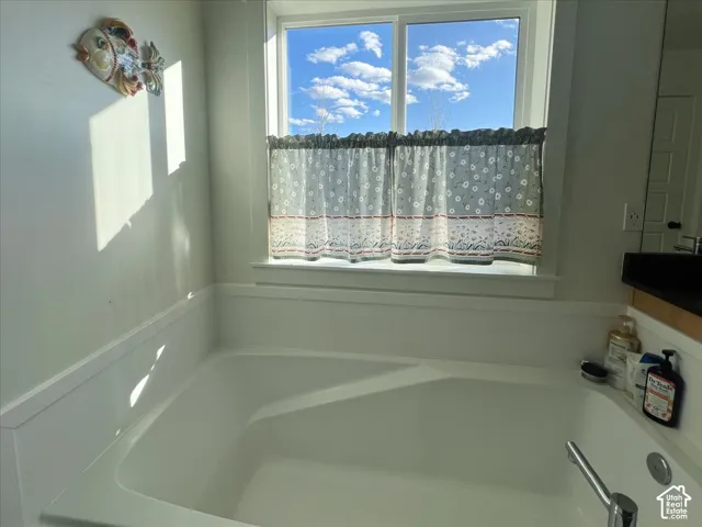 Soaking tub with a polished chrome faucet, a large window, and wainscoting
