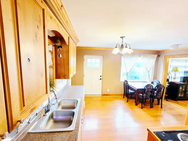 Kitchen featuring wood cabinetry, a double basin stainless steel sink, and wood-finish flooring