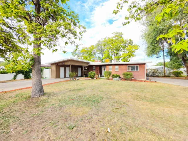 Red brick exterior with white trim, covered entryway, mature landscaping, and a paved driveway