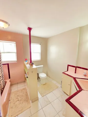 Tiled flooring throughout, built-in shelving, two windows, and a built-in vanity with tiled countertop