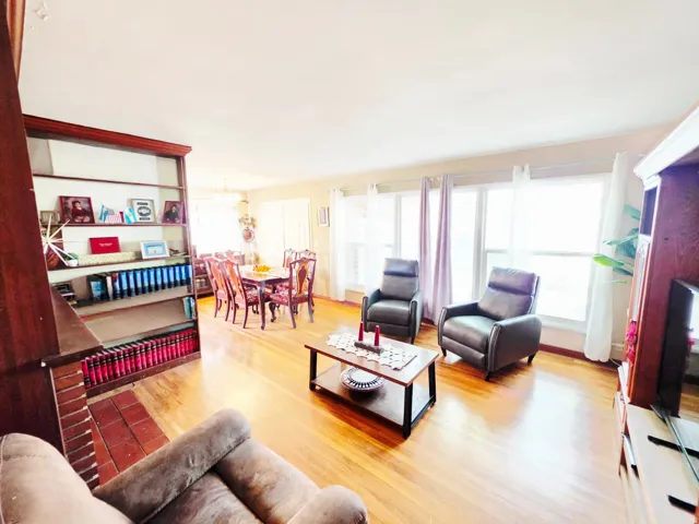 Hardwood flooring throughout, built-in shelving with brick detailing, multiple windows, and a dedicated dining area
