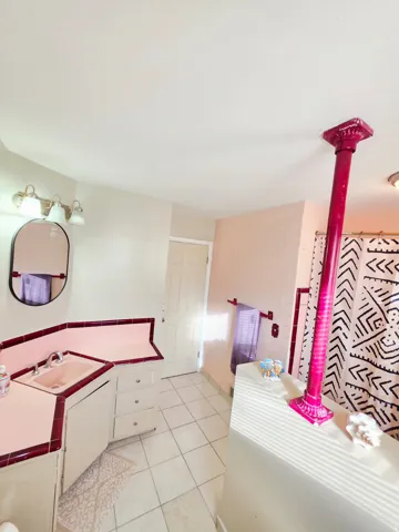 Bathroom featuring a corner vanity with integrated sink, tiled countertop, and a vanity light fixture