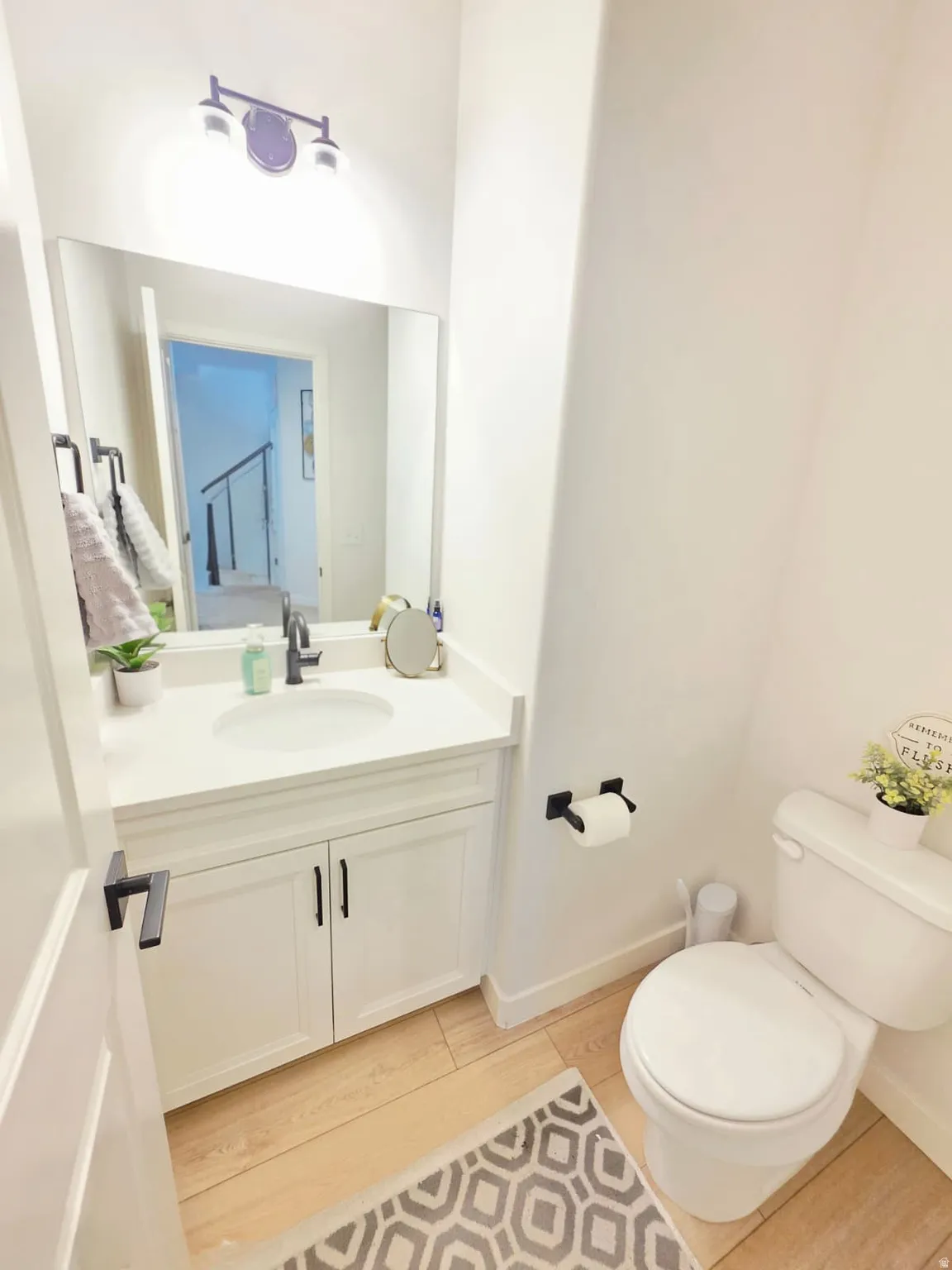 White vanity with a single basin sink, white countertop, and black hardware
