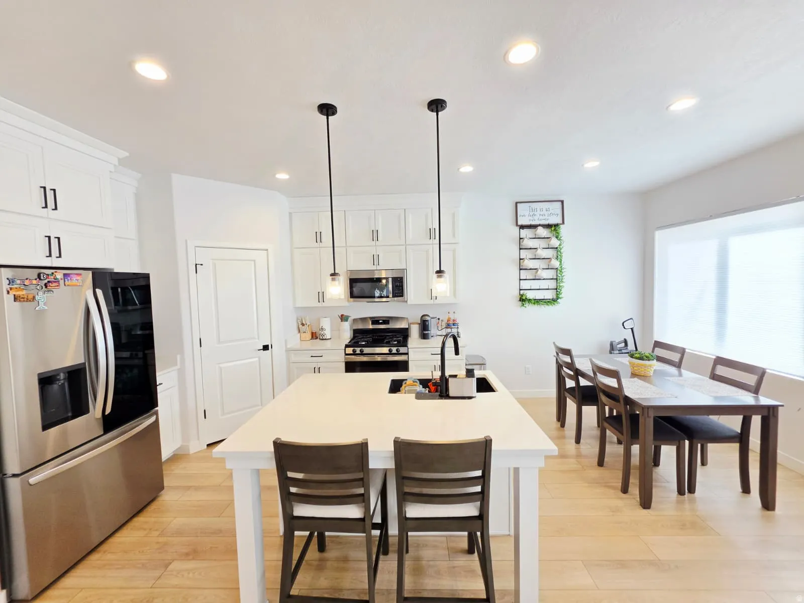 Kitchen featuring white cabinetry, stainless steel appliances, a center island with countertop seating, recessed lighting, and wood-finish flooring