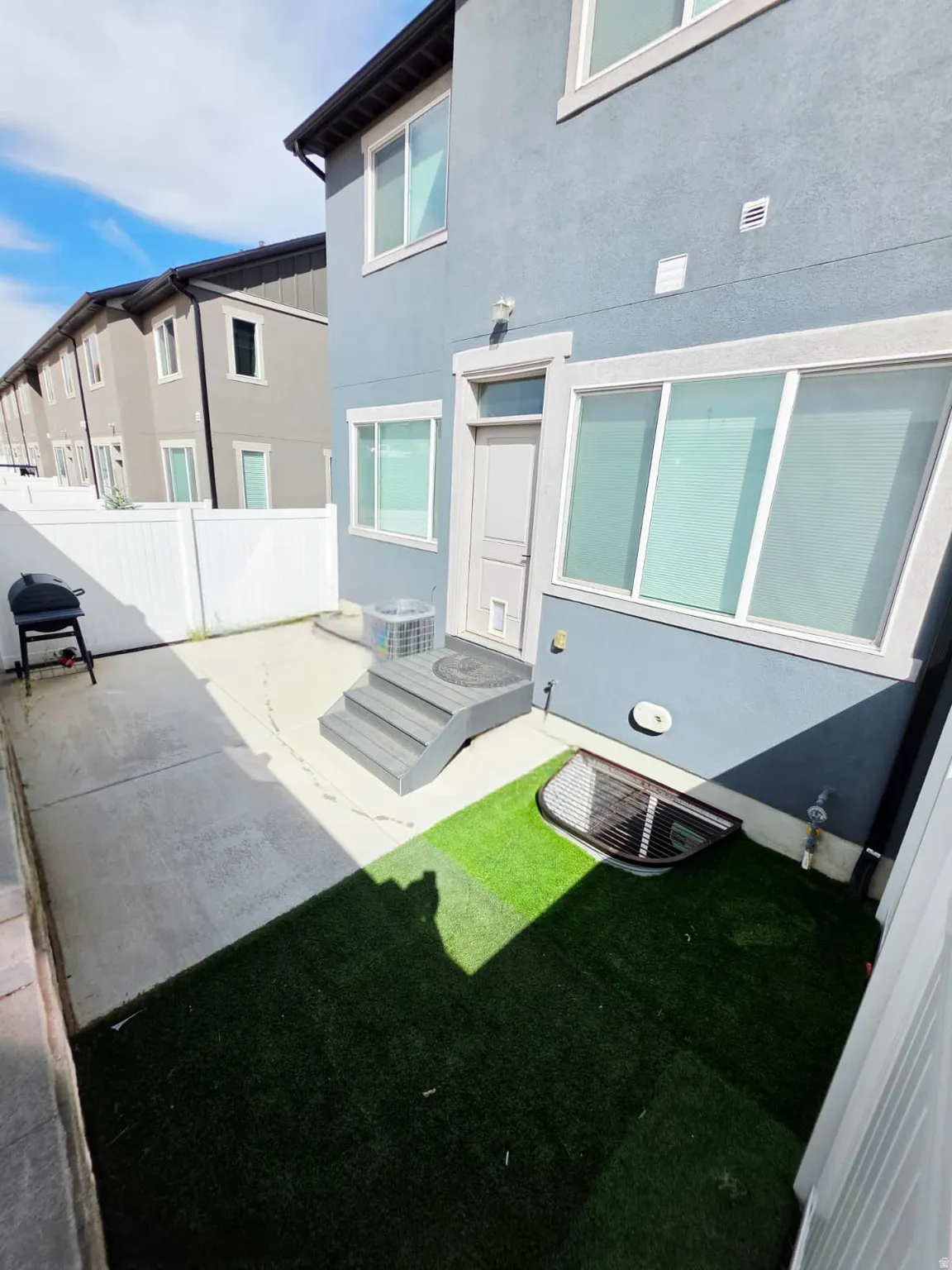 Private fenced yard featuring artificial turf and concrete patio