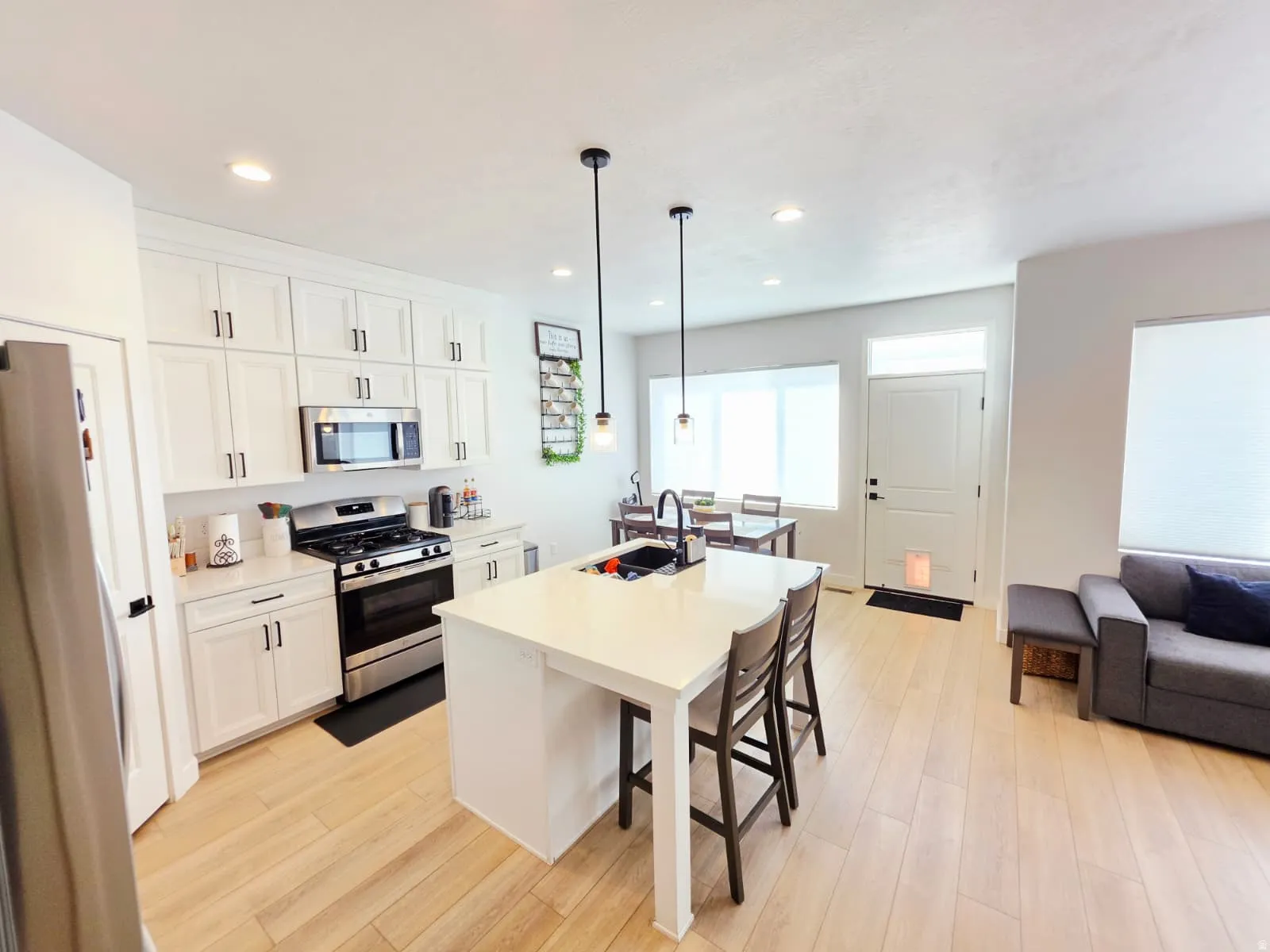 Bright open-concept kitchen featuring white cabinetry, stainless steel appliances, and a central island with countertop seating