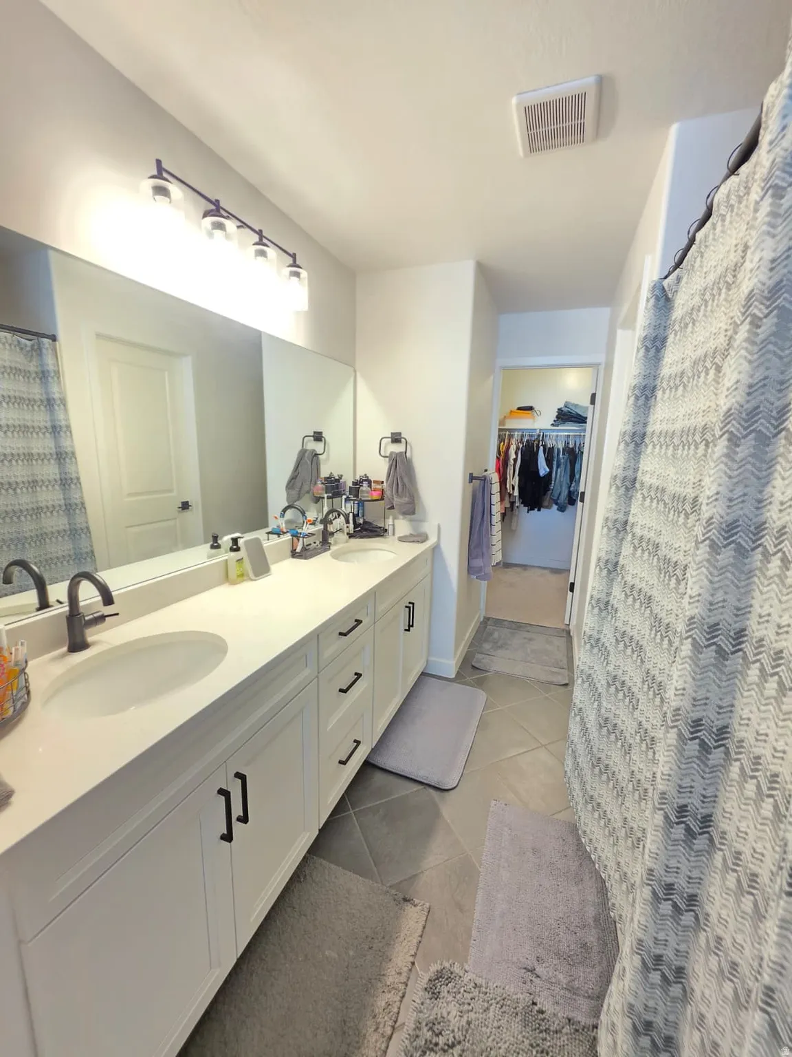 Dual vanity with undermount sinks, white cabinetry, dark hardware, and a large mirror