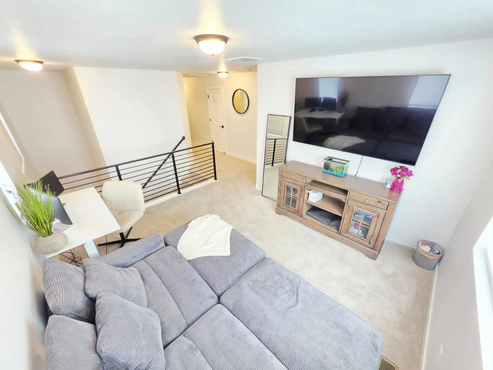 Carpeted loft area featuring modern black metal railings, recessed lighting, and a light-colored accent wall