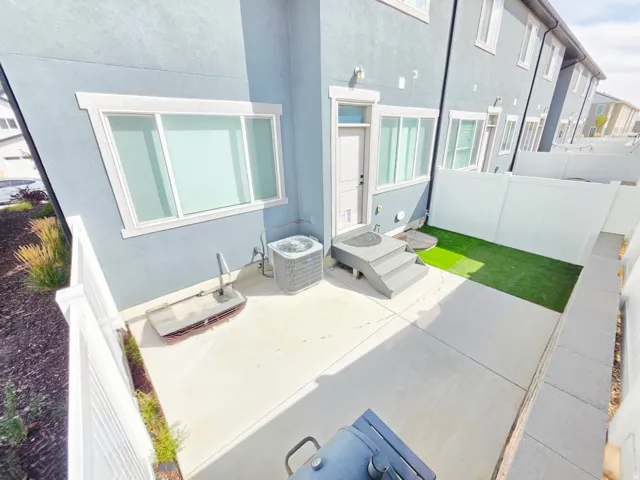 Private patio with concrete surfacing, artificial turf area, and privacy fencing