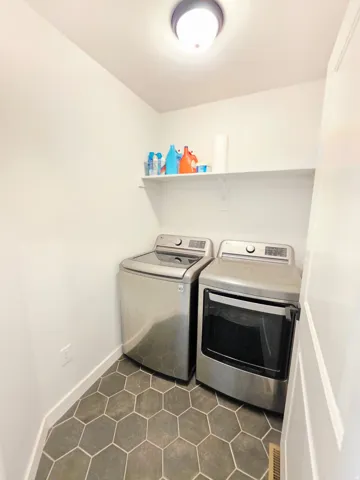 Compact laundry area featuring hexagonal floor tiles and a wall-mounted storage shelf