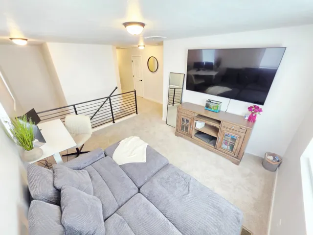 Carpeted loft area featuring modern black metal railings, recessed lighting, and a light-colored accent wall