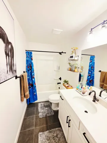 White vanity with black cabinet hardware, white countertop with integrated sink, and black faucet