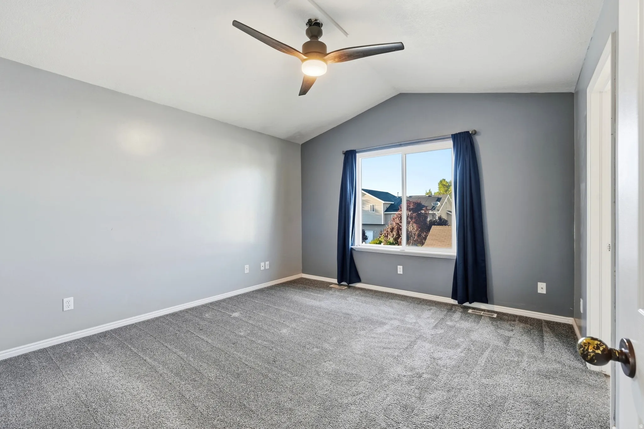 Vaulted ceiling with an attached ceiling fan, dual-pane window, and wall-to-wall carpeting