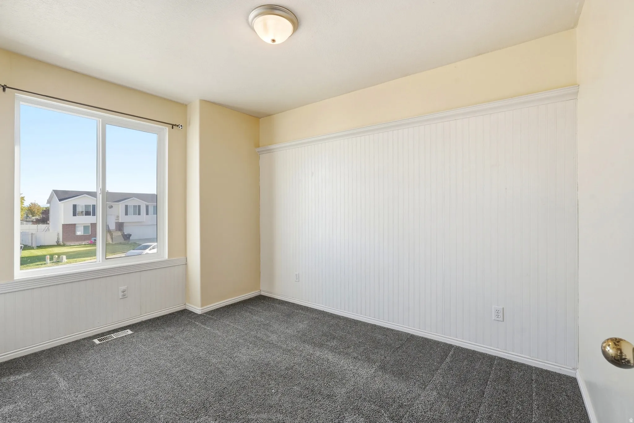White beadboard wainscoting, neutral tone walls, recessed ceiling light, and gray carpet flooring