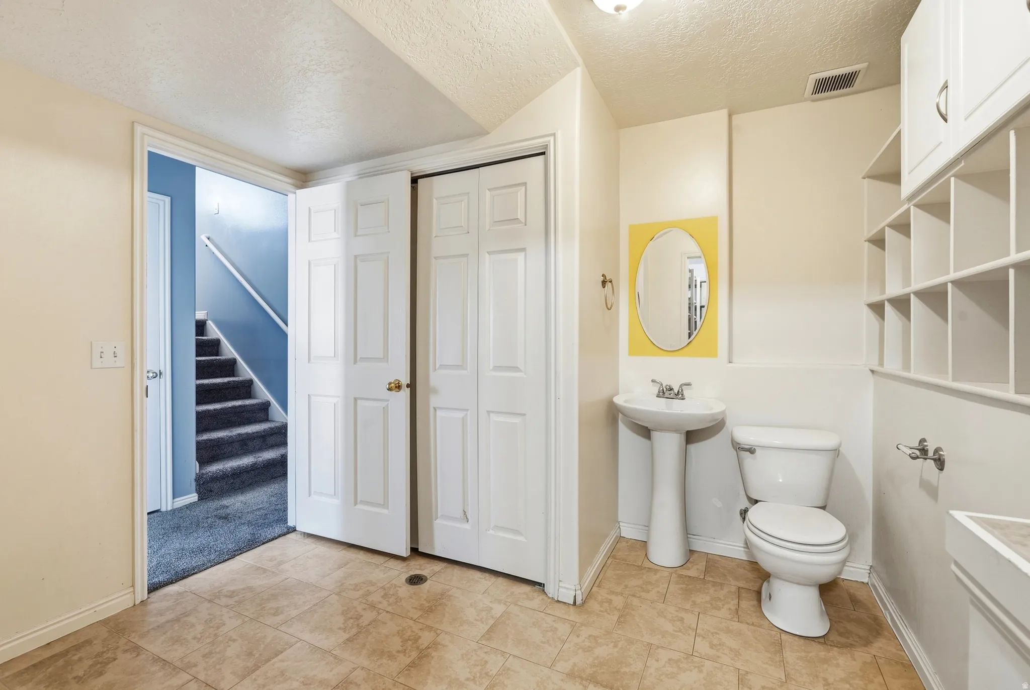 Pedestal sink, toilet, and built-in shelving with upper cabinetry
