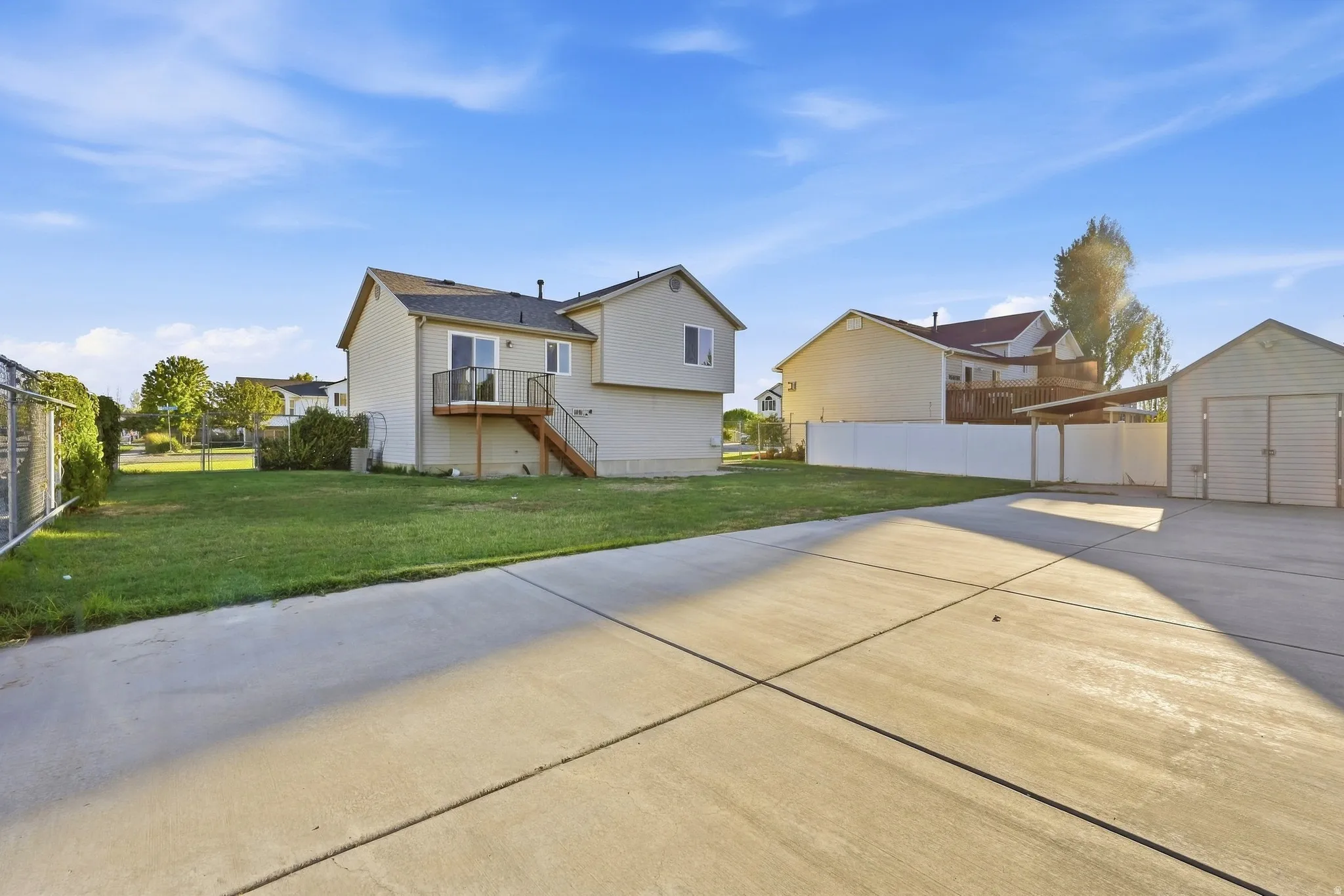 Expansive concrete driveway and patio area, detached shed, and a covered carport structure