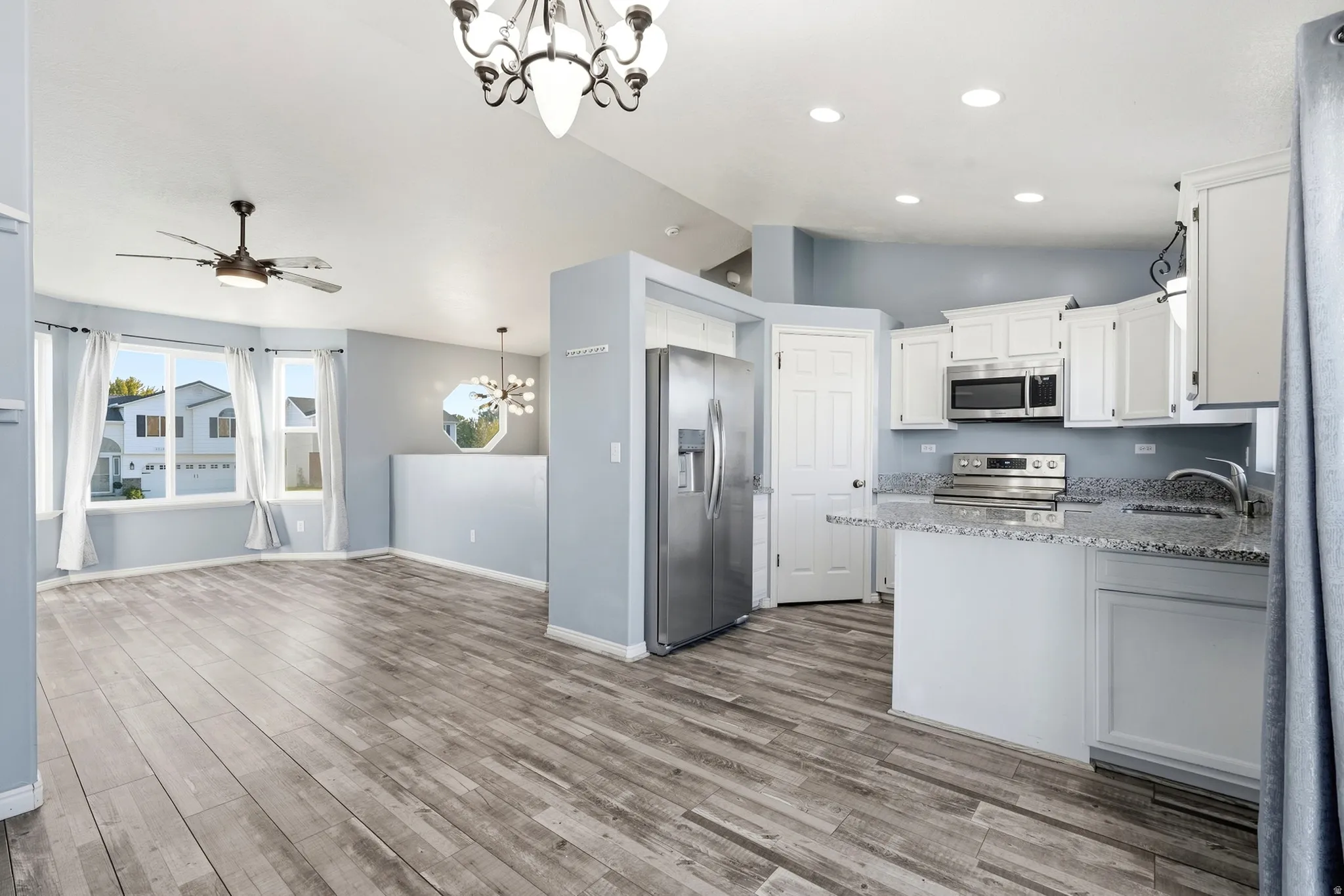 Integrated kitchen with white cabinetry, stainless steel appliances, and granite countertops