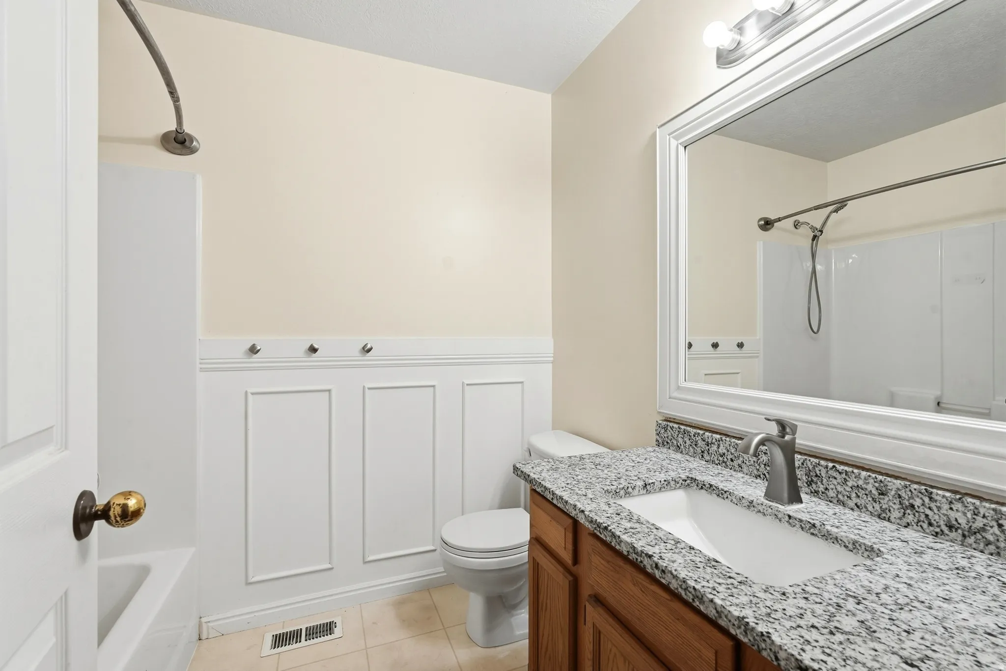Vanity with stone countertop, integrated sink, and wood-finish cabinetry