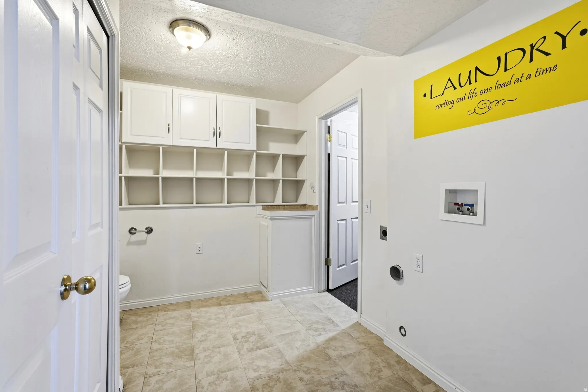 White cabinetry, open cubby shelving, a built-in countertop, and neutral-toned flooring