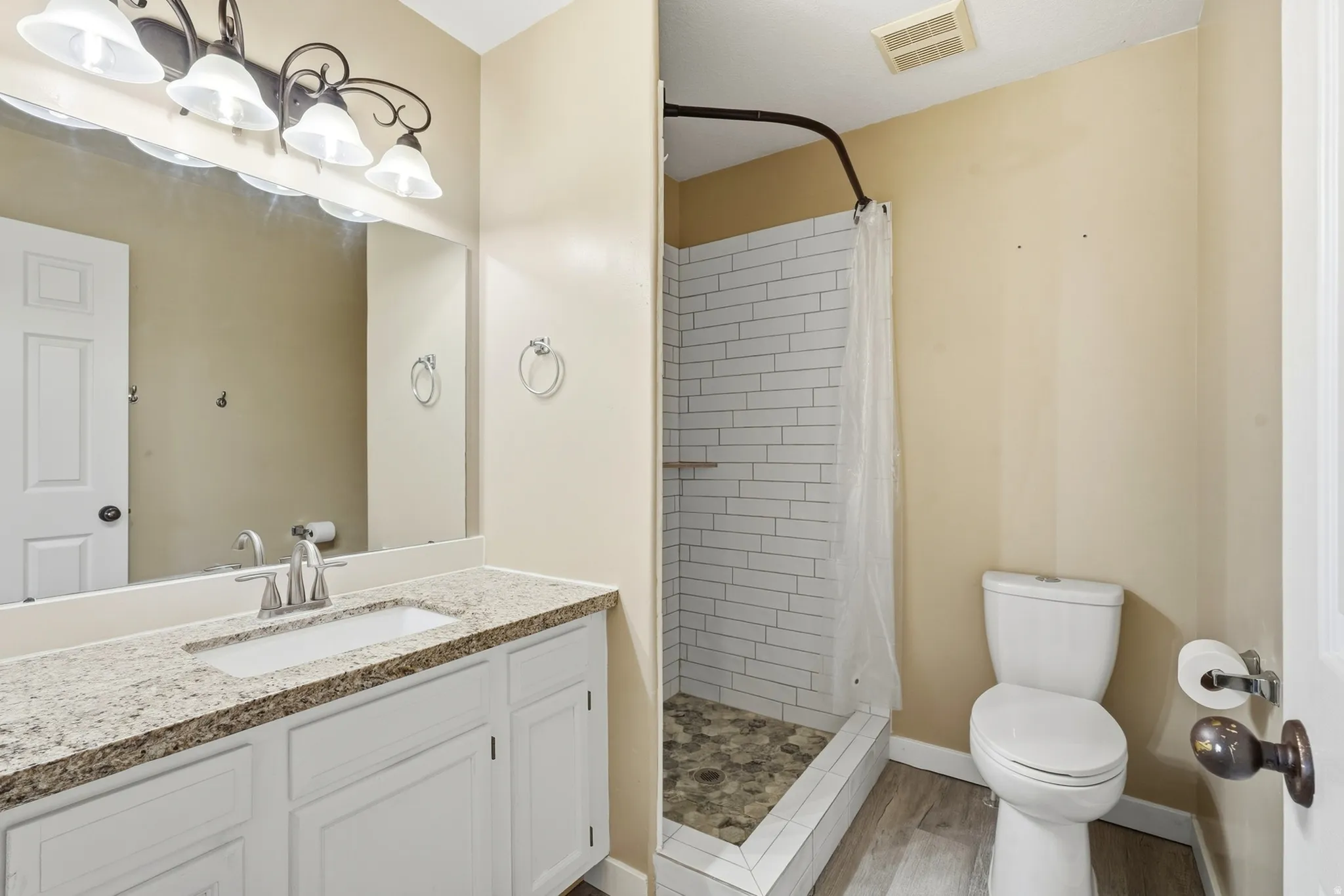 White vanity with a light-toned countertop, rectangular sink, and chrome faucet