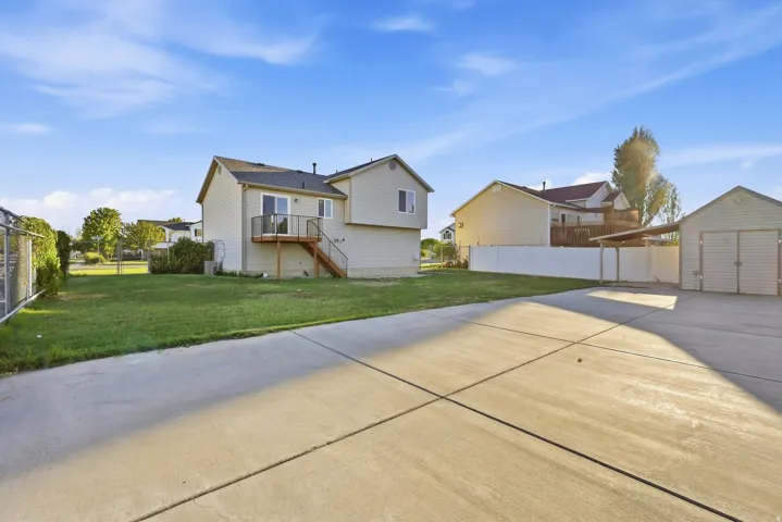 Expansive concrete driveway and patio area, detached shed, and a covered carport structure