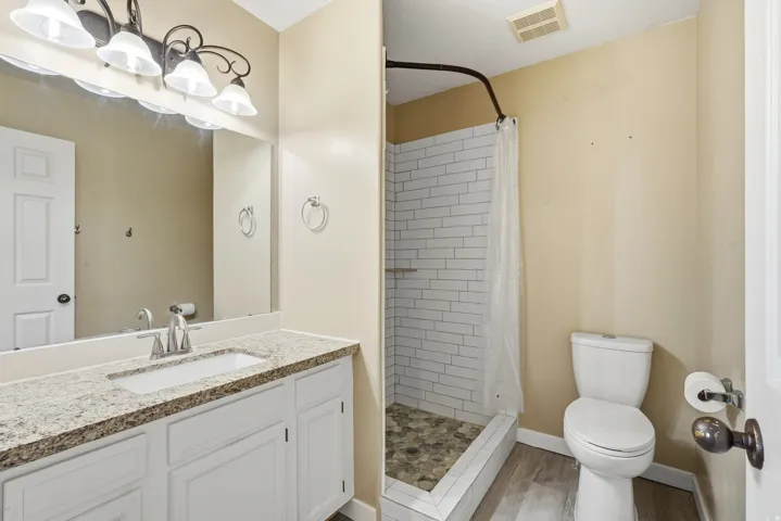 White vanity with a light-toned countertop, rectangular sink, and chrome faucet