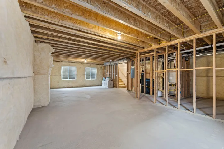 Unfinished basement with exposed wood framing, concrete flooring, spray foam insulation, and visible sub-floor joists