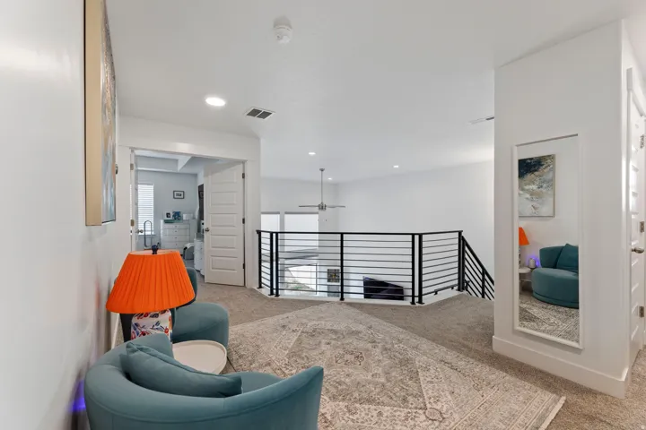 Carpeted upper-level landing with a contemporary metal railing system, recessed lighting, and white paneled doors