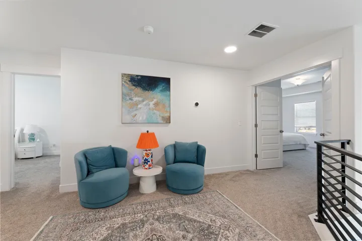 Carpeted landing with recessed lighting, white walls, and a black metal railing