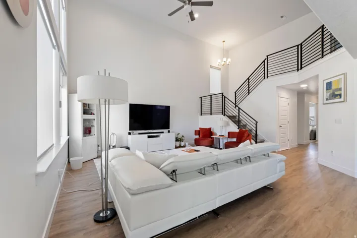 Vaulted ceilings, wood-finish flooring, and a contemporary open-riser staircase with horizontal metal railings
