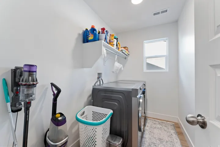Utility space featuring a window, built-in shelving, and wood-finish flooring